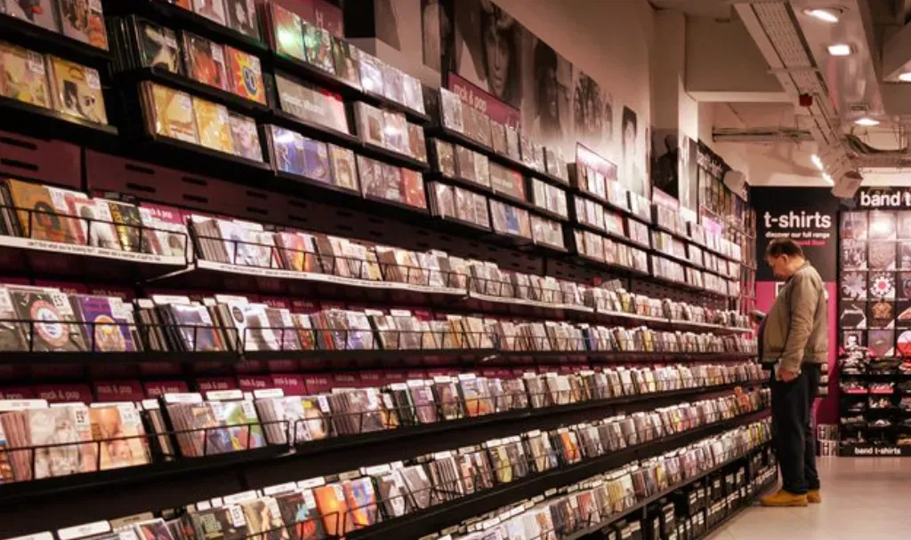 Hombre revisando discos en los estantes de una tienda de música con cientos de CD