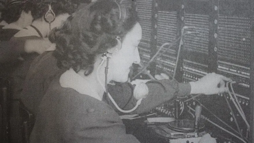 Fotografía antigua de una operadora conectando cables en una centralita telefónica manual