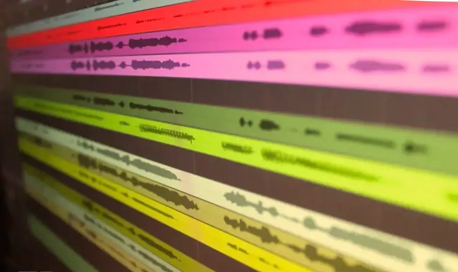 Pantalla de un programa de grabación con pistas de colores y formas de onda de audio