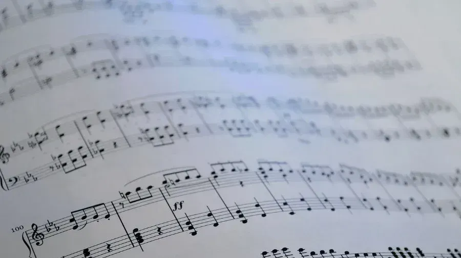Partitura impresa de piano desenfocada, con pentagramas y líneas de compás