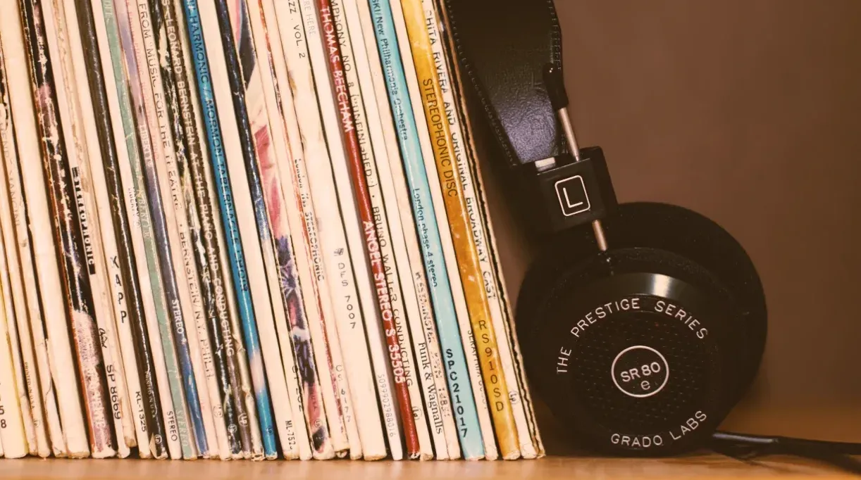 Hilera de discos de vinilo antiguos en un estante junto a unos audífonos de diadema