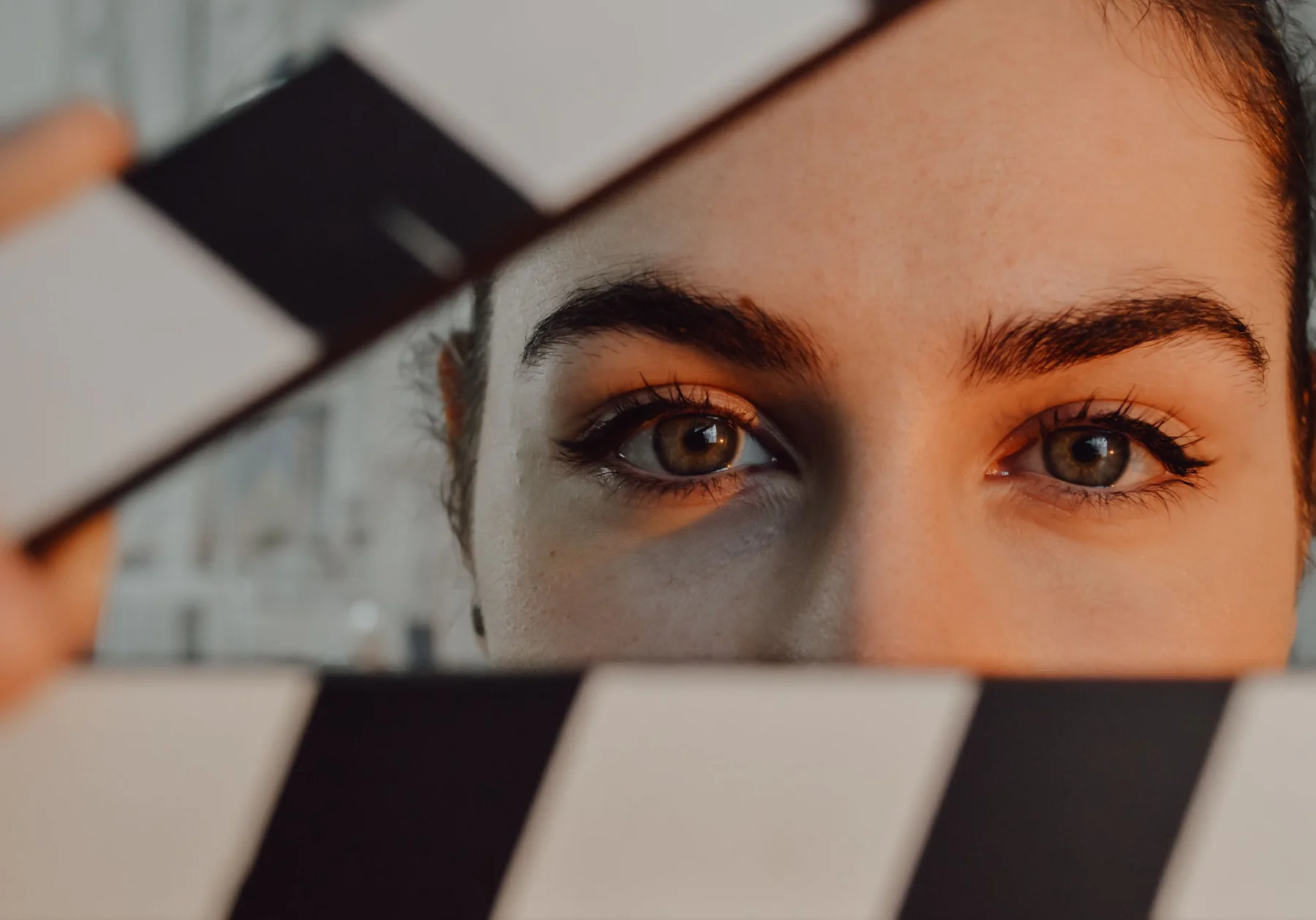 Mirada de una joven entre las tablas de una claqueta de cine