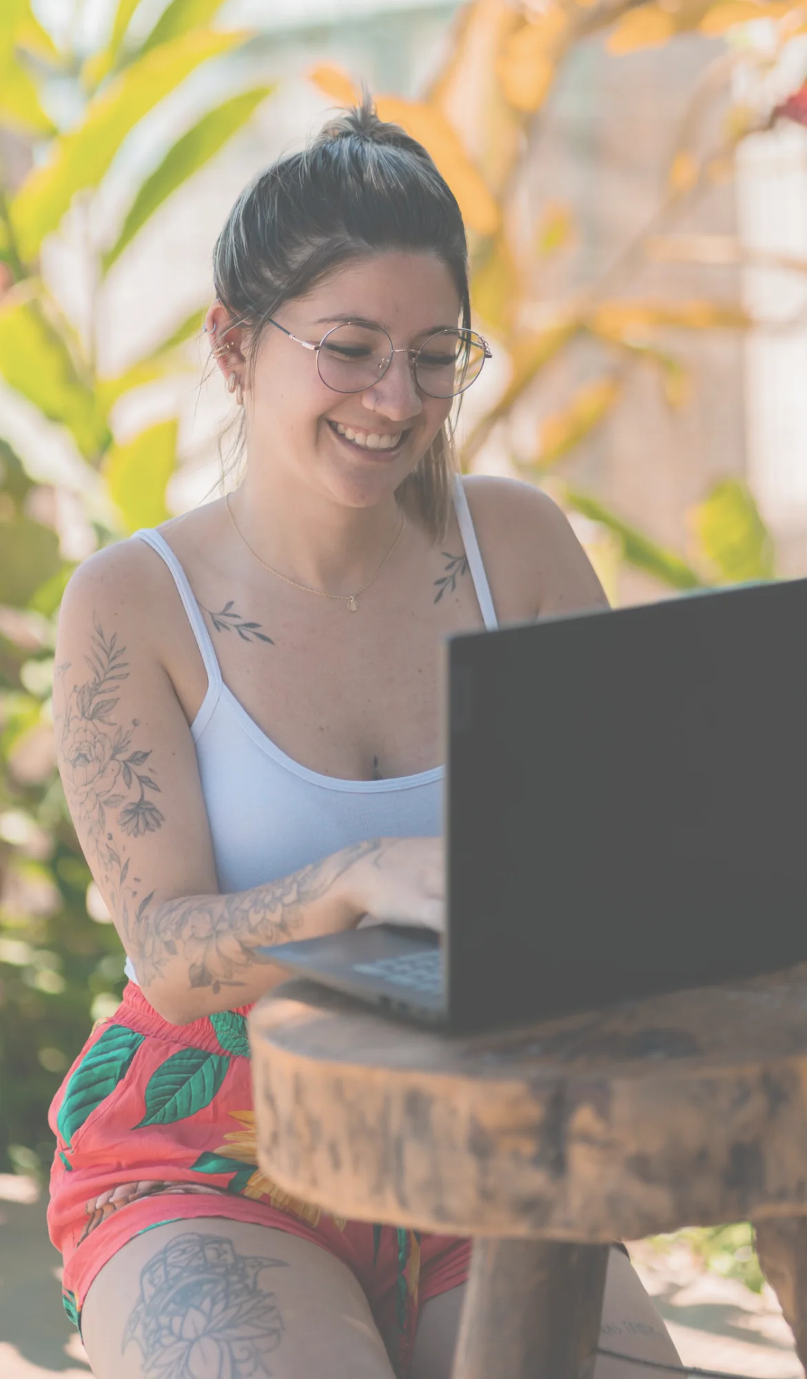 Estudiante sonriendo mientras toma una clase en su laptop al aire libre